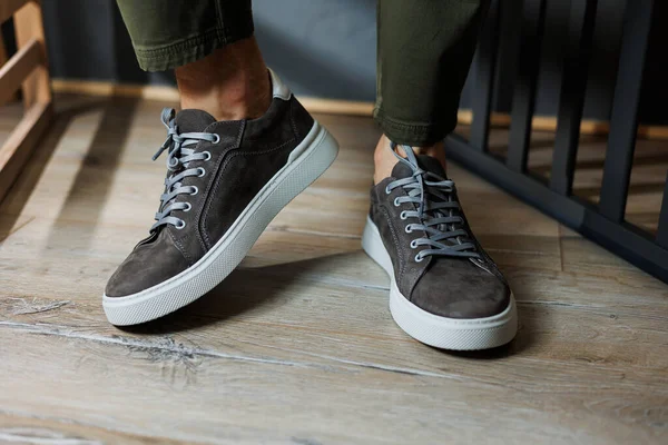 Close-up of male legs in pants and gray casual sneakers. Men\'s leather shoes. Collection of men\'s stylish summer shoes