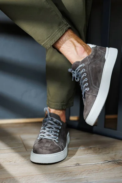 Close-up of male legs in pants and gray casual sneakers. Men\'s leather shoes. Collection of men\'s stylish summer shoes