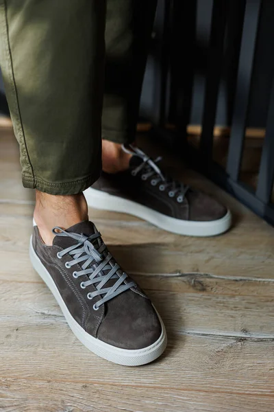Close-up of male legs in pants and gray casual sneakers. Men's leather shoes. Collection of men's stylish summer shoes