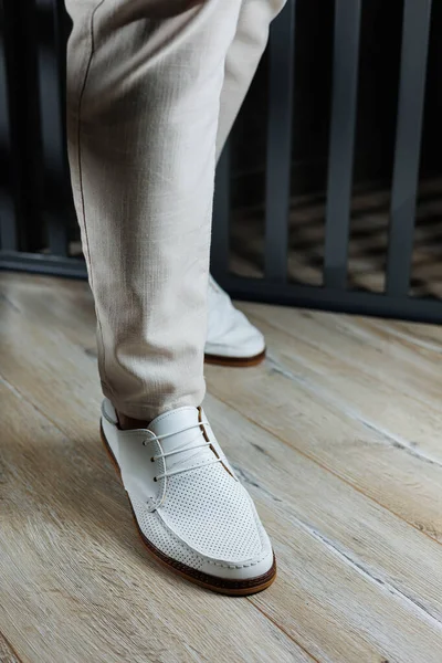 Male legs in leather summer shoes. Comfortable men\'s white moccasins without laces. Casual men\'s moccasins