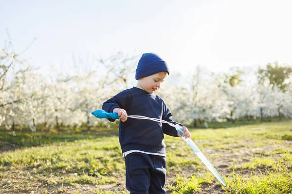 stock image A three-year-old boy runs through a blooming garden with soap bubbles. Cheerful emotional child is walking in the park. Soap bars for children