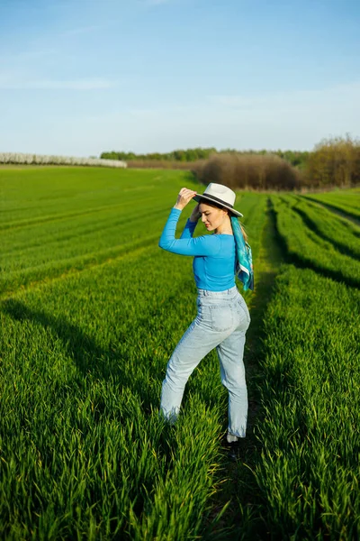 청바지와 모자를 귀여운 들판에 있습니다 파란색 청바지를 미소짓는 여자가 잔디를 — 스톡 사진