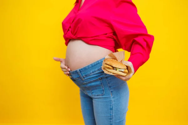 Cheerful Pregnant Woman Pink Shirt Holding Hamburger Isolated Yellow Background — Stock Photo, Image