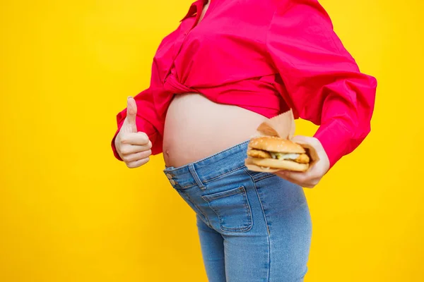 Vrolijke Zwangere Vrouw Roze Shirt Met Hamburger Geïsoleerde Gele Achtergrond — Stockfoto