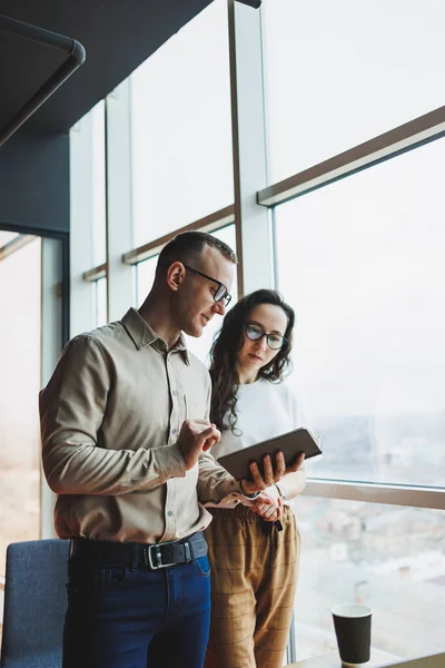 stock image Young male and female colleagues work in a spacious office. Successful people are working on a new business project. Collective work in the office