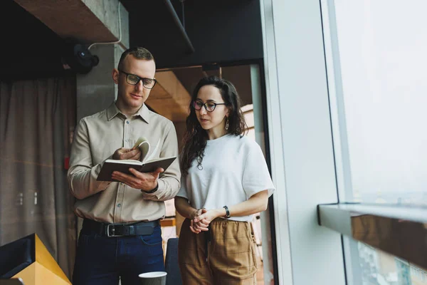 stock image Young male and female colleagues work in a spacious office. Successful people are working on a new business project. Collective work in the office