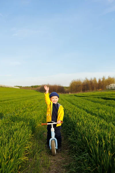 一个小男孩骑一辆蓝色的平衡自行车 骑自行车 一个快乐的孩子正在花园里学习如何在自行车上保持平衡 一个孩子在街上玩耍 骑自行车的第一天 — 图库照片