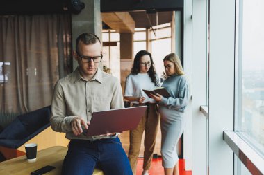 Bir grup başarılı iş adamı ofiste bir arada duruyorlar ve modern bir çalışma ofisinde iş kurarken birbirleriyle konuşuyorlar. İş arkadaşlarınla ofiste çalış..