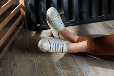 Bej renkli spor ayakkabılarla dar pantolonlu, ince kadın bacakları. Kadın deri ayakkabıları..