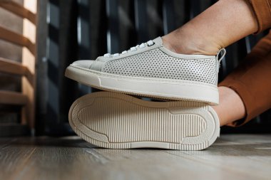 Bej renkli spor ayakkabılarla dar pantolonlu, ince kadın bacakları. Kadın deri ayakkabıları..