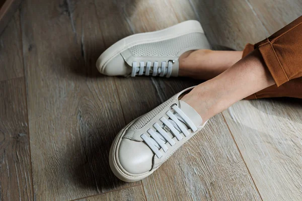 stock image Slender female legs in pants close-up in beige casual sneakers. Women's leather shoes.