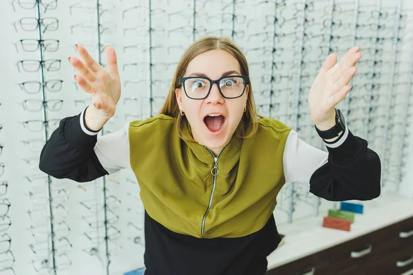 一个可爱的女人在眼科商店里选择眼镜 女人买眼镜 一个站在商店橱窗后面的女人 戴着不同款式的眼镜 — 图库照片