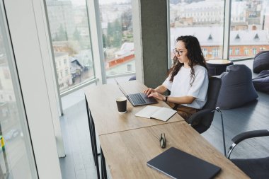 Günümüz ofis çalışanı günlük giysiler içinde bir dizüstü bilgisayarda çalışır. İş yerindeki bayan yönetici dizüstü bilgisayarla yeni bir proje üzerinde çalışıyor. modern çalışma alanı