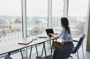 Günümüz ofis çalışanı günlük giysiler içinde bir dizüstü bilgisayarda çalışır. İş yerindeki bayan yönetici dizüstü bilgisayarla yeni bir proje üzerinde çalışıyor. modern çalışma alanı