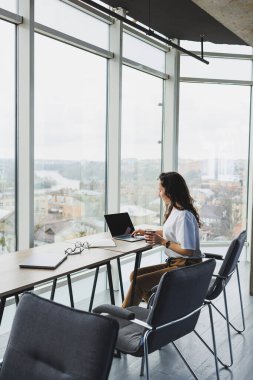 Günümüz ofis çalışanı günlük giysiler içinde bir dizüstü bilgisayarda çalışır. İş yerindeki bayan yönetici dizüstü bilgisayarla yeni bir proje üzerinde çalışıyor. modern çalışma alanı