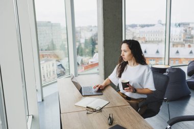 Günümüz ofis çalışanı günlük giysiler içinde bir dizüstü bilgisayarda çalışır. İş yerindeki bayan yönetici dizüstü bilgisayarla yeni bir proje üzerinde çalışıyor. modern çalışma alanı