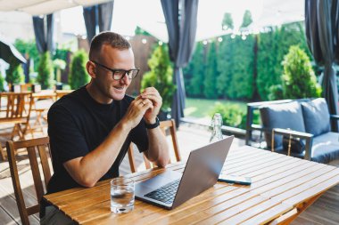 Siyah tişörtlü ve gözlüklü başarılı bir erkek serbest yazar bir kafenin yaz terasında oturur ve bir dizüstü bilgisayarda çalışır. Müdür öğle yemeği sırasında bir kafede oturur ve internette çalışır..