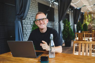 Siyah tişörtlü ve gözlüklü başarılı bir erkek serbest yazar bir kafenin yaz terasında oturur ve bir dizüstü bilgisayarda çalışır. Müdür öğle yemeği sırasında bir kafede oturur ve internette çalışır..