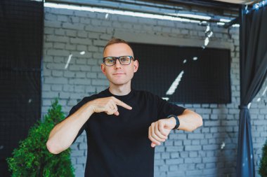 Gözlüklü ve siyah tişörtlü hoş bir genç adam bir kafede bir terasta duruyor ve kameraya bakıp gülümsüyor. İnternette uzak bir yaz işi. Görüş düzeltmesi için erkek gözlüğü