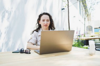 Laptopta yazan konsantre kız öğrenci kafede fincan ile çalışırken, düşünceli serbest yazar proje planlaması için bilgi yazar, dizüstü bilgisayarla uzaktan iş yapar.