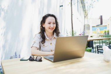 Laptopta yazan konsantre kız öğrenci kafede fincan ile çalışırken, düşünceli serbest yazar proje planlaması için bilgi yazar, dizüstü bilgisayarla uzaktan iş yapar.