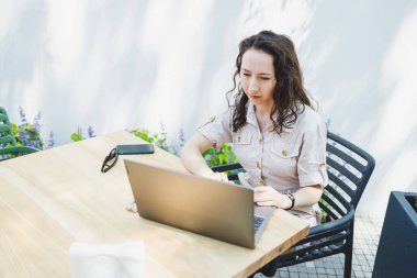 Laptopta yazan konsantre kız öğrenci kafede fincan ile çalışırken, düşünceli serbest yazar proje planlaması için bilgi yazar, dizüstü bilgisayarla uzaktan iş yapar.