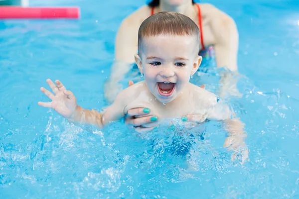 stock image A 2-year-old boy learns to swim in a pool with a coach. Swimming lessons for children. Swimming school for children. Educational swimming courses for children