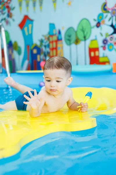 小さな陽気な2歳の少年がプールで泳ぐことを学んでいる 子供のための水泳レッスン 子供のための水泳学校 ストック写真