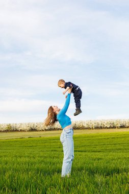 Genç bir anne ve oğlu yeşil çimlerin üzerinde yatıyor. Anne ve çocuğun aile ilişkileri. Mutlu bir aile.