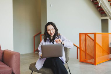 Çevrimiçi parlak kafede çalışan kıvırcık kız öğrenci dizüstü bilgisayara bakıyor. Samimi bir kafede dizüstü bilgisayarla uzaktan çalışma