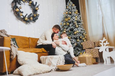 Küçük bir çocuklu mutlu bir genç aile Noel ağacının yanında yeni yılı evde kutluyor. Aileyle Noel, Yeni Yıl - kutlama zamanı.