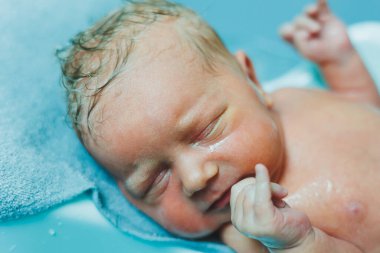 Yeni doğmuş bir bebek küvette yatıyor. Yeni doğmuş bir bebeğin ilk banyosu. Yeni doğmuş bir bebeği yıkıyorum..