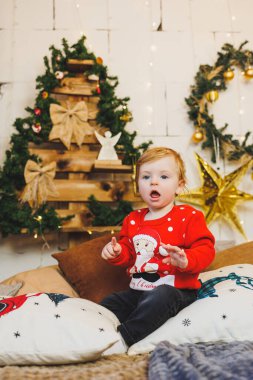 Evdeki Noel süslemelerinin arka planında gülümseyen bir çocuk. Ev Yeni Yıl atmosferi.