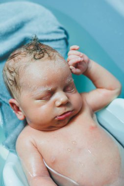 Yeni doğmuş bir bebek banyo yapmak için küvette yatıyor. Bebeği yıkıyorum. Yeni doğanların ve çocukların hijyeni.