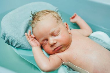 Yeni doğmuş bir bebek banyo yapmak için küvette yatıyor. Bebeği yıkıyorum. Yeni doğanların ve çocukların hijyeni.