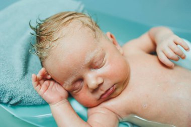 Yeni doğmuş bir bebek banyo yapmak için küvette yatıyor. Bebeği yıkıyorum. Yeni doğanların ve çocukların hijyeni.