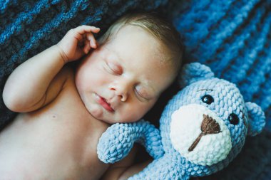 Yeni doğmuş bir bebek örülmüş bir oyuncak ayıyla uyur. Çocukların ördüğü oyuncaklar. Bebek uyuyor.