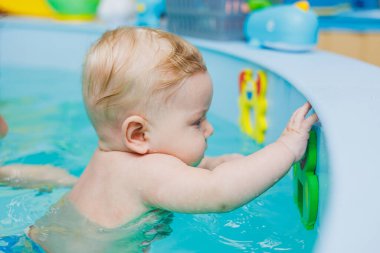 5 aylık bir bebek bir koçla havuzda yüzmeyi öğrenir. Bebek yüzmeyi öğreniyor.