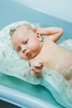 Yeni doğmuş bir bebek banyoda ağlıyor. Yeni doğmuş bir bebeği küvette yıkamak. Yeni doğmuş bir bebeğin ilk banyosu..