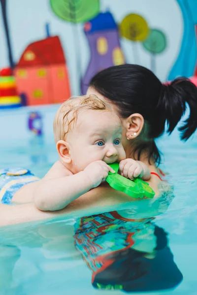 Teaching children to swim. A baby learns to swim in a pool with a trainer. Baby learning to swim. Child development.