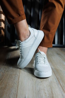 Beyaz delikli deri ayakkabılarla kadın bacaklarının yakın çekimi. Kadın yaz ayakkabıları. Kadın deri ayakkabı koleksiyonu.