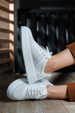 Beyaz delikli deri ayakkabılarla kadın bacaklarının yakın çekimi. Kadın yaz ayakkabıları. Kadın deri ayakkabı koleksiyonu.