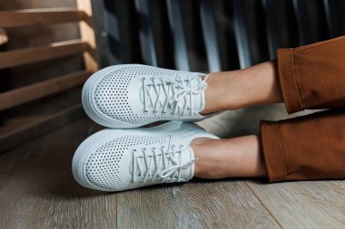 Beyaz delikli deri ayakkabılarla kadın bacaklarının yakın çekimi. Kadın yaz ayakkabıları. Kadın deri ayakkabı koleksiyonu.