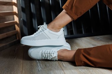 Beyaz delikli deri ayakkabılarla kadın bacaklarının yakın çekimi. Kadın yaz ayakkabıları. Kadın deri ayakkabı koleksiyonu.