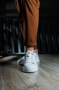 Düz tabanlı bağcıklı kadın ayakkabıları. Beyaz delikli deri ayakkabılarla kadın bacaklarının yakın çekimi. Kadın yaz ayakkabıları. Kadın deri ayakkabı koleksiyonu.