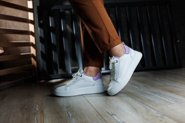 Düz tabanlı bağcıklı kadın ayakkabıları. Beyaz delikli deri ayakkabılarla kadın bacaklarının yakın çekimi. Kadın yaz ayakkabıları. Kadın deri ayakkabı koleksiyonu.