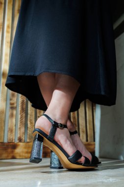 Siyah deri sandaletlerle ince kadın bacakları. Yazlık kadın ayakkabıları koleksiyonu. Yaz için şık kadın ayakkabıları. Kadınların ayaklarında kadın sandaletleri