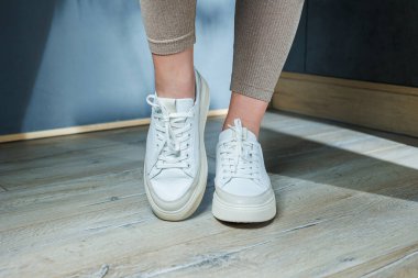 Ayakta beyaz deri kadın klasik spor ayakkabısı. Yaz için şık kadın ayakkabıları. Yaz kadın ayakkabısı koleksiyonu.