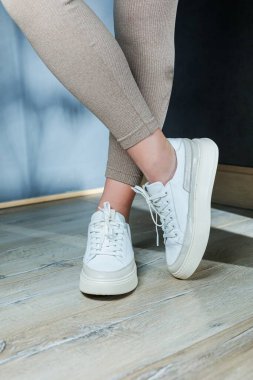 Ayakta beyaz deri kadın klasik spor ayakkabısı. Yaz için şık kadın ayakkabıları. Yaz kadın ayakkabısı koleksiyonu.