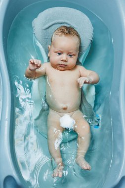 Bebeği küvette yıkarken, bebek plastik bir tezgahta yatıyor. Bebek bakımı.